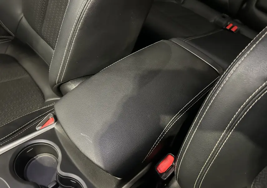 Gros plan sur l'accoudoir central en cuir noir avec surpiqûres blanches entre les sièges avant du Renault Kadjar bleu 2017.