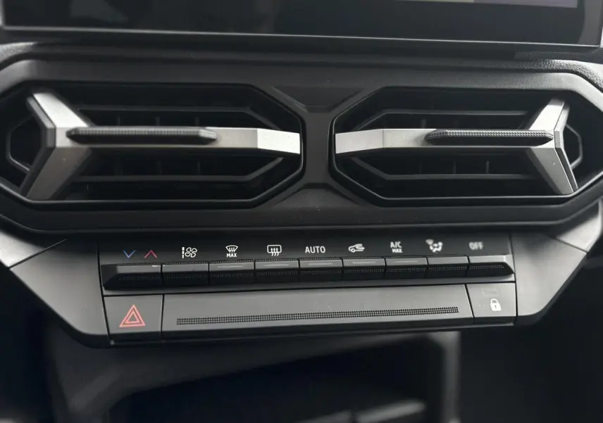 Détail des commandes de climatisation et aérateurs hexagonaux noirs du tableau de bord du Dacia Duster blanc Glacier 2025.