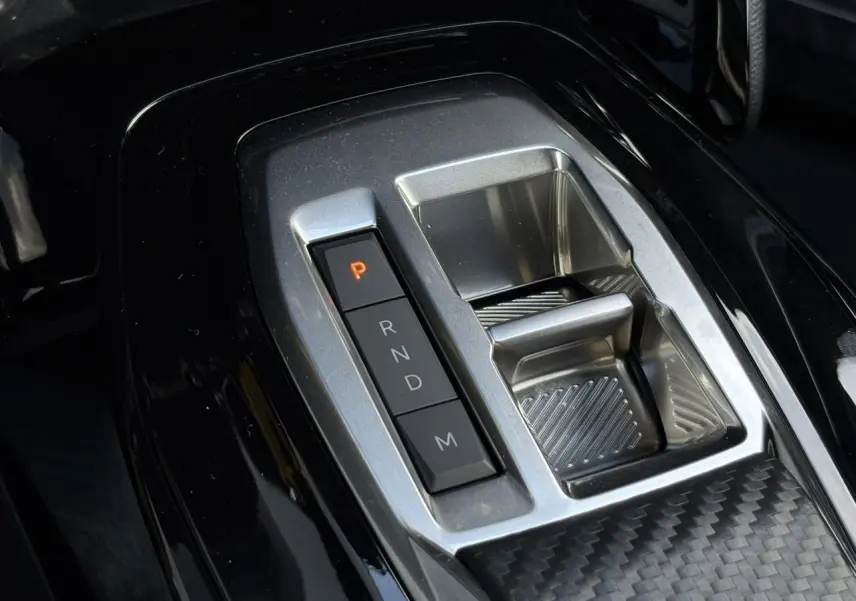 Gros plan sur la console centrale noire et argentée avec sélecteur de boîte automatique du Peugeot 2008 Hybrid 145 e-DSC6 Allure.