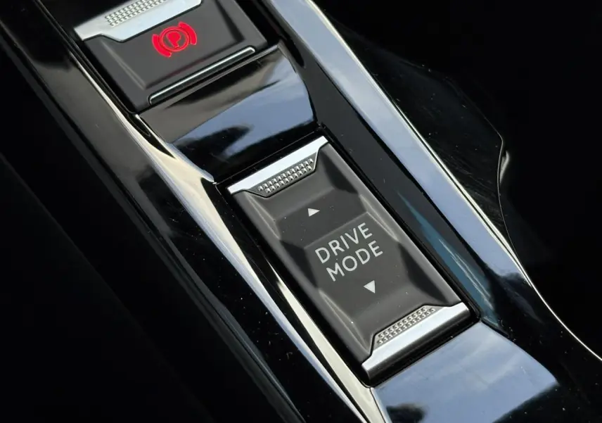 Gros plan sur la console centrale noire brillante du Peugeot 2008 Hybrid 145 e-DSC6 Allure avec bouton Drive Mode et frein électrique.