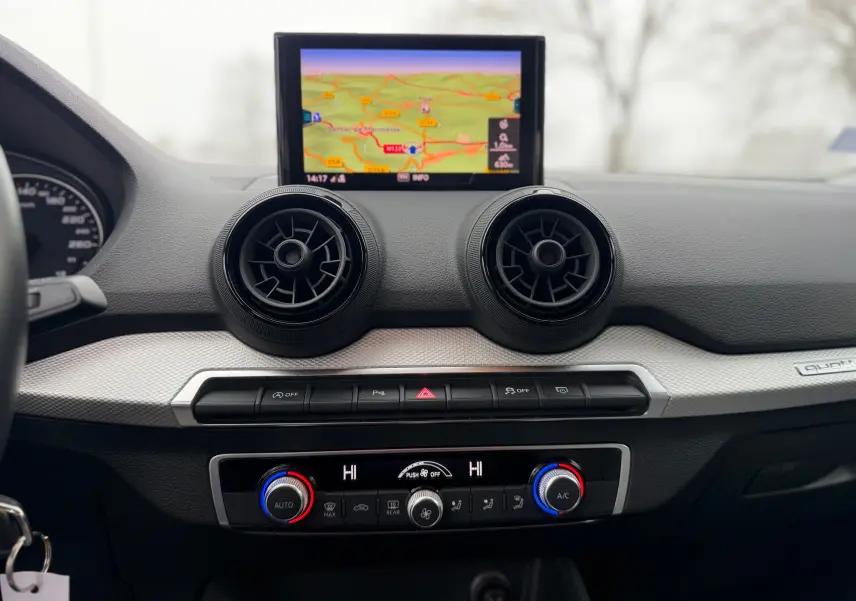 Vue rapprochée du tableau de bord gris d’un Audi Q2 2017 avec écran GPS et commandes de climatisation circulaires.