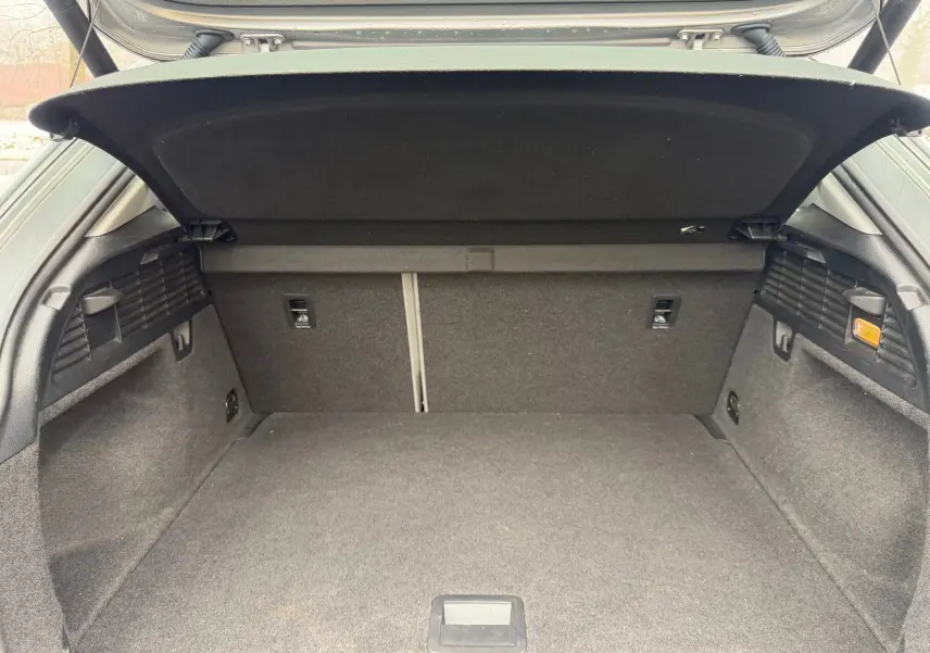Coffre ouvert vu de l'arrière d'un Audi Q2 gris aluminium, montrant un espace de chargement propre et spacieux.