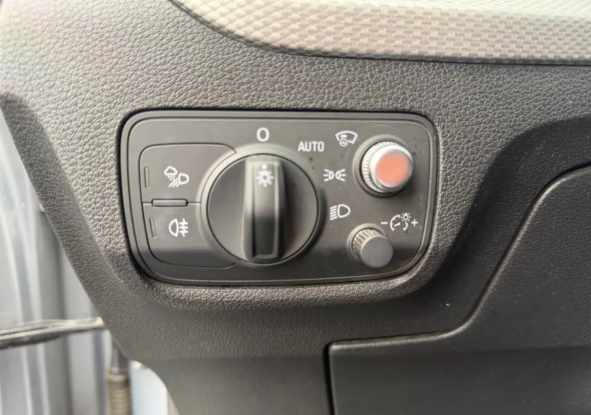 Gros plan sur la commande des phares et réglages lumineux dans l'habitacle de l'Audi Q2 gris aluminium.