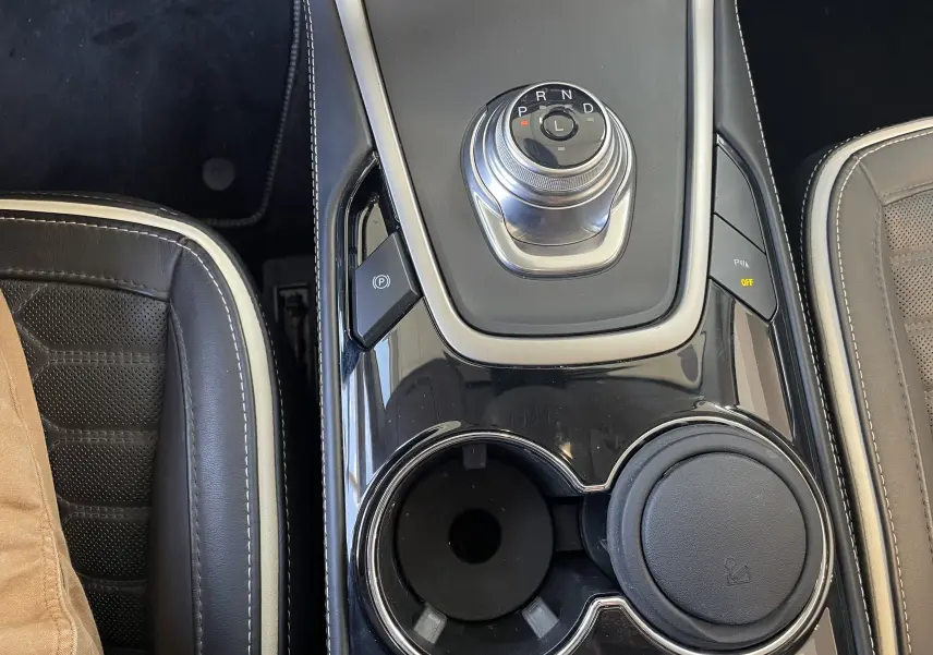 Vue rapprochée de la console centrale du Ford S-MAX Vignale gris, avec molette de boîte auto et porte-gobelets.