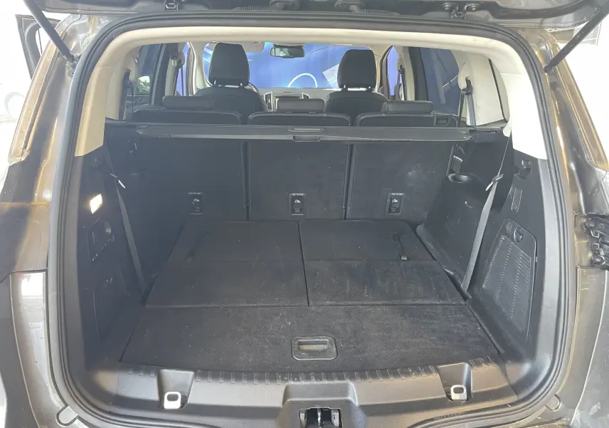 Vue arrière du coffre spacieux du Ford S-MAX Vignale gris magnetic 2022 avec sièges rabattus et cache-bagages déployé.