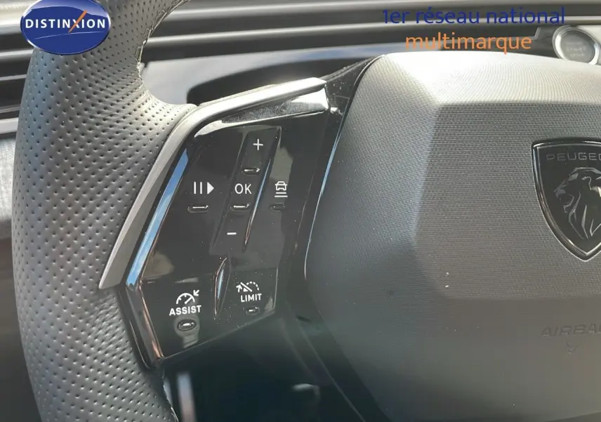 Gros plan sur le volant perforé du Peugeot 3008 2025, avec commandes multifonctions et logo lion central.