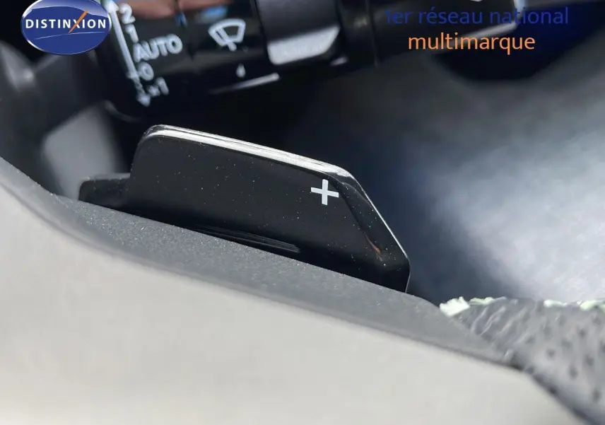 Gros plan sur la palette de changement de vitesse "+" du Peugeot 3008 hybride 2025 avec intérieur noir.