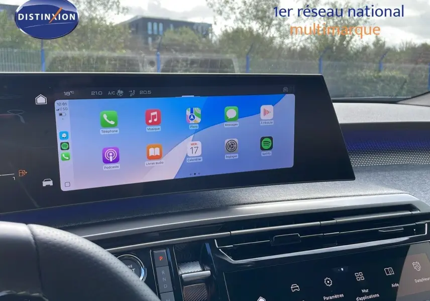 Vue intérieure du tableau de bord du Peugeot 3008 hybride 2025 avec écran tactile central affichant des applications colorées.