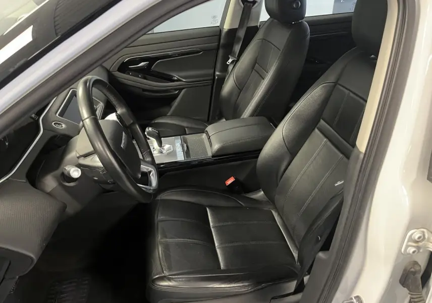 Intérieur côté conducteur du Range Rover Evoque blanc 2020 avec sièges cuir noirs et console centrale élégante.