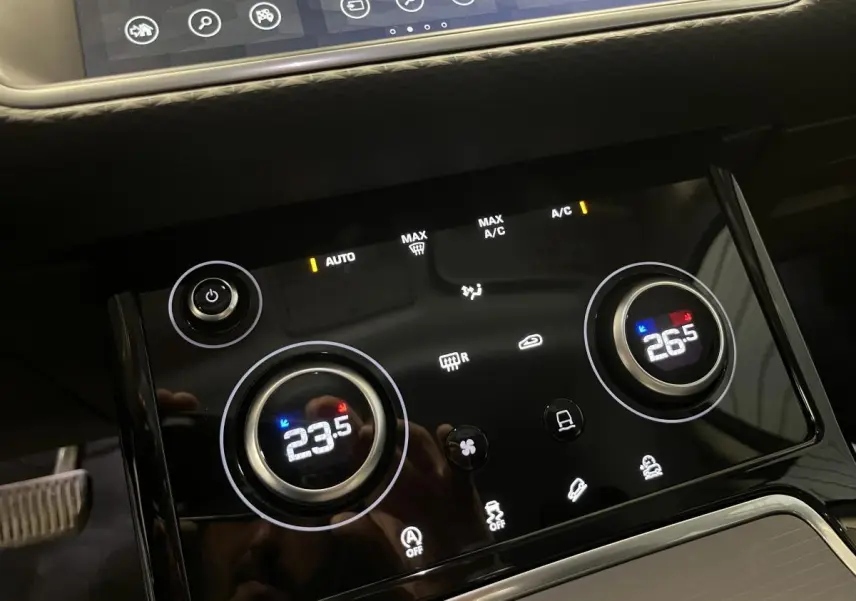 Panneau de commande de la climatisation bi-zone tactile du Range Rover Evoque blanc, affichant 23,5°C à gauche et 26,5°C à droite.