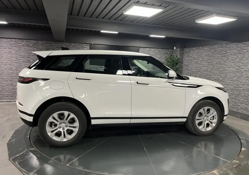 Profil côté gauche d'un Range Rover Evoque blanc 2020 avec jantes 18 pouces dans un garage intérieur.