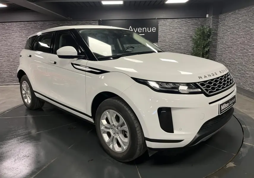 Range Rover Evoque blanc en 3/4 avant droit, avec calandre noire et jantes argentées dans un showroom.