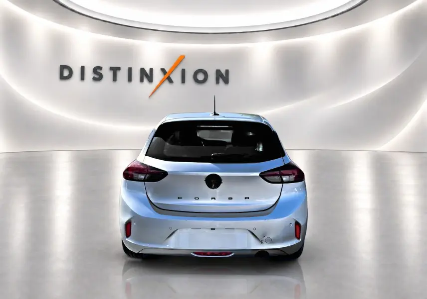 Vue arrière d'une Opel Corsa gris alu 2025 dans un showroom lumineux avec logo Distinxion en arrière-plan.