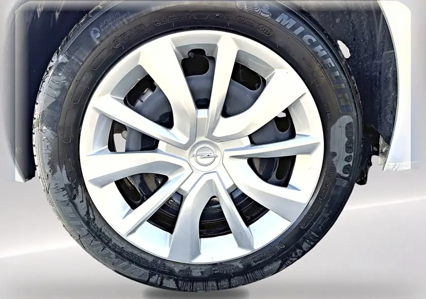 Gros plan sur la roue avant droite d’une Opel Corsa gris alu avec jante en alliage et logo Opel central.