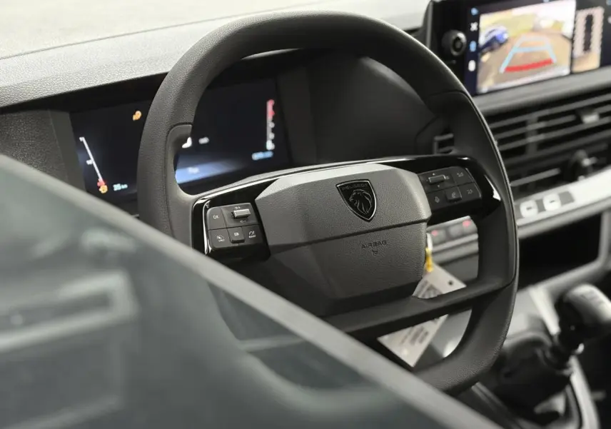 Vue rapprochée du volant Peugeot avec commandes intégrées et écran tactile affichant la caméra de recul.