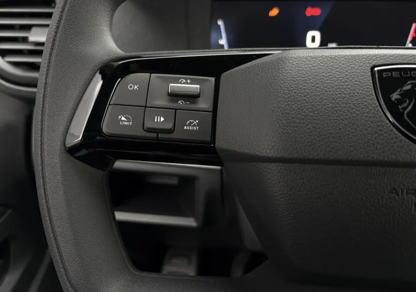 Gros plan sur les commandes à gauche du volant noir du Peugeot Expert Fourgon 2025 avec boutons de limitation et assistance.