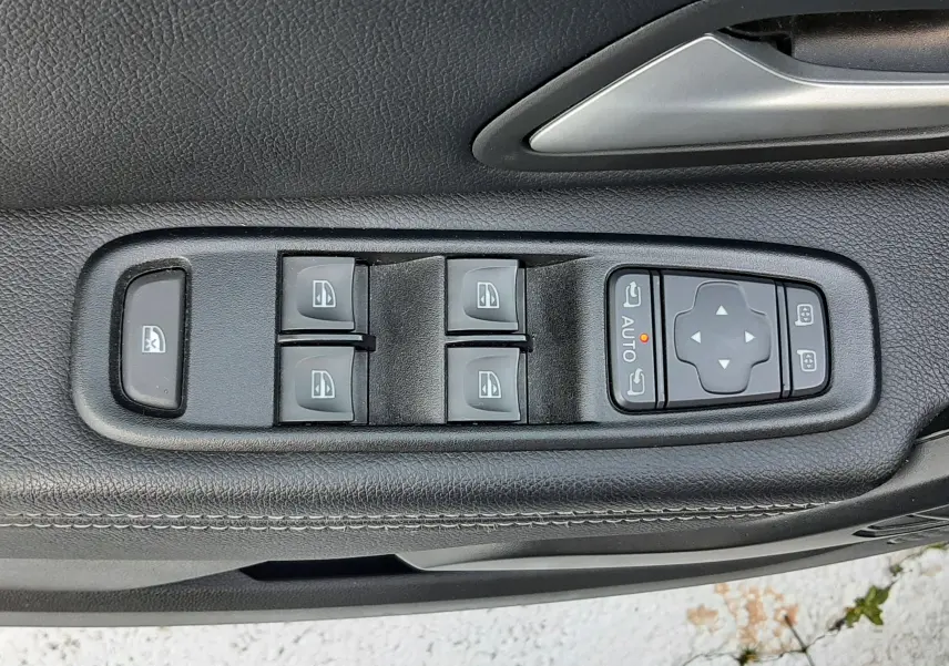 Gros plan sur les commandes des vitres et rétroviseurs côté conducteur d'un Dacia Duster 2023, intérieur noir.