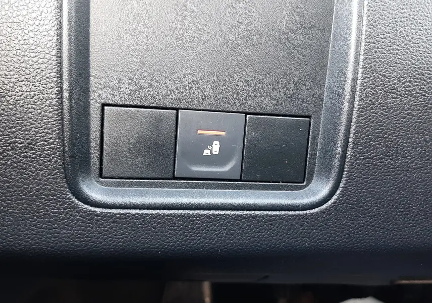 Gros plan sur le bouton de verrouillage centralisé noir dans l'habitacle du Dacia Duster bleu 2023.