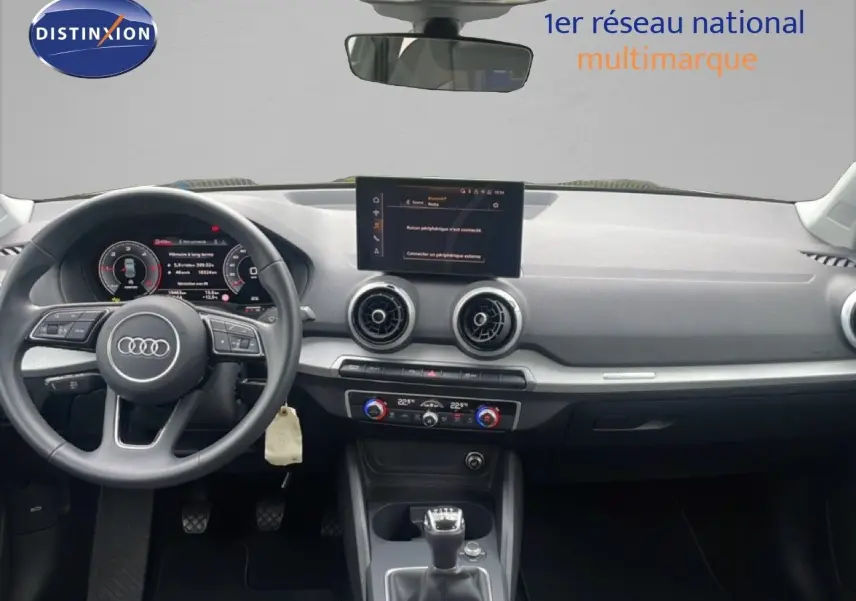 Vue intérieure avant de l'Audi Q2 30 TDI S-Line 2025, tableau de bord noir avec écran central et volant cuir multifonction.