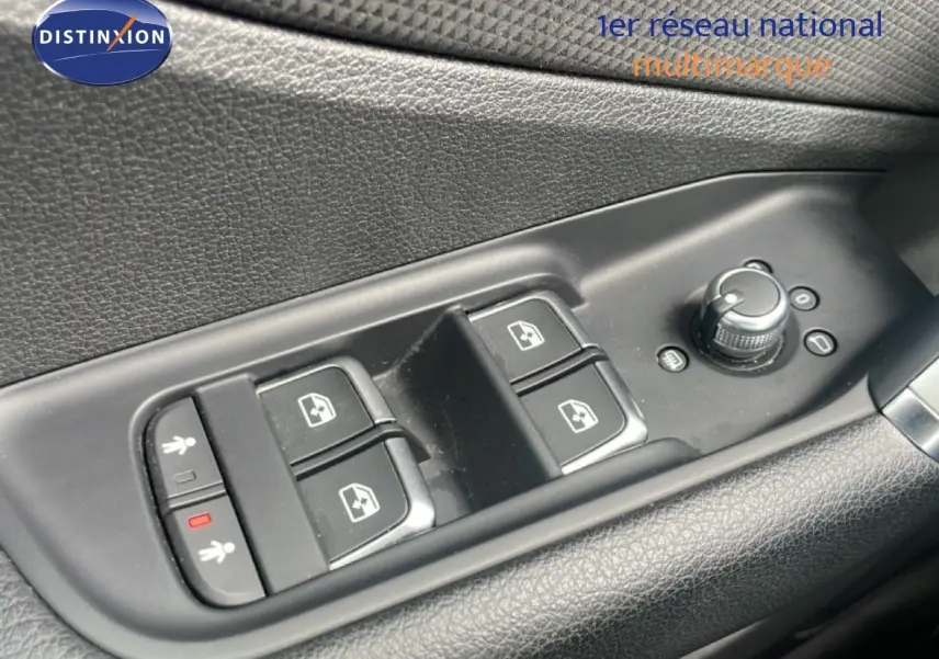 Gros plan sur les commandes de lève-vitres et réglage des rétroviseurs côté conducteur d’un Audi Q2 noir mito metal.