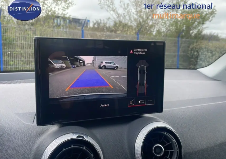 Écran central affichant la caméra de recul avec guidage en bleu dans l’Audi Q2 noir mito metal, vue intérieure avant.