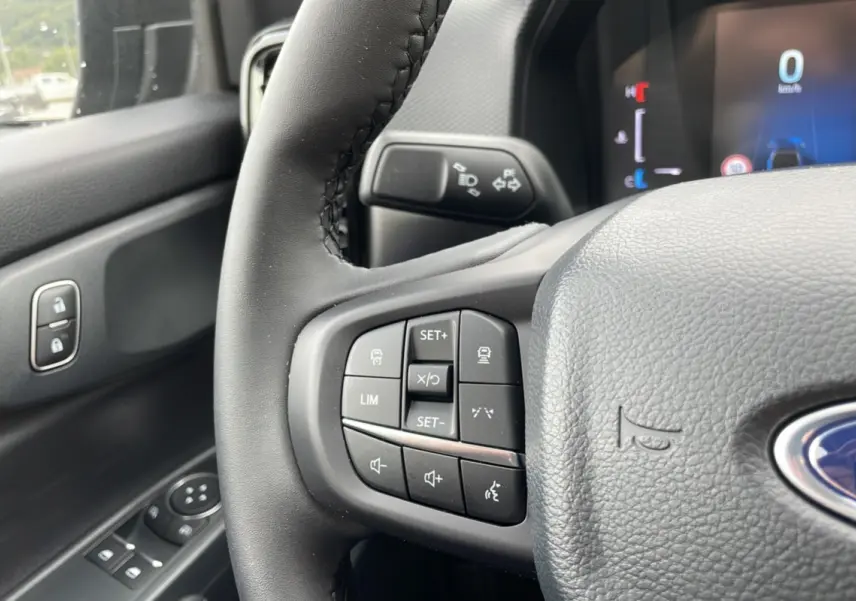 Vue rapprochée du volant cuir gris du Ford Ranger 2025 avec commandes multifonctions et tableau de bord digital.