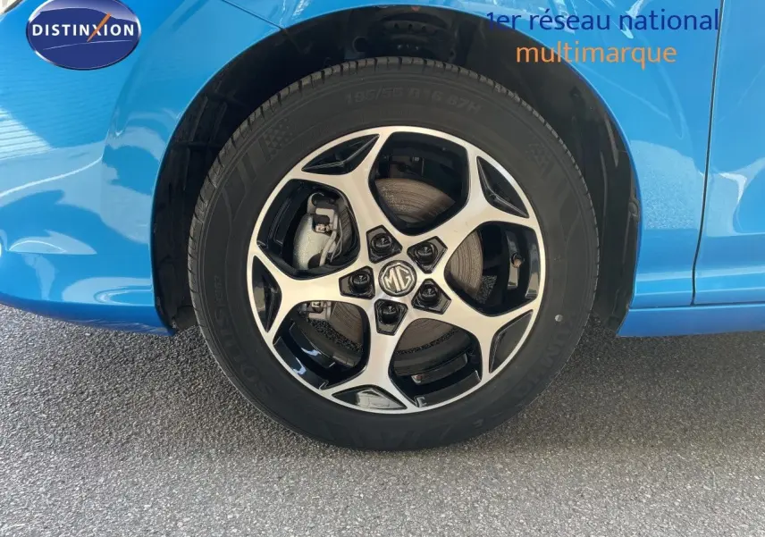 Gros plan sur la roue avant droite d'une MG3 2024 bleu Como Metal avec jante alliage bicolore et logo MG au centre.