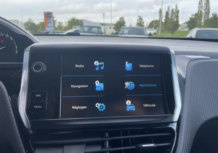 Écran tactile central du tableau de bord d'un Peugeot 2008 gris, affichant les menus radio, navigation, téléphone et véhicule.