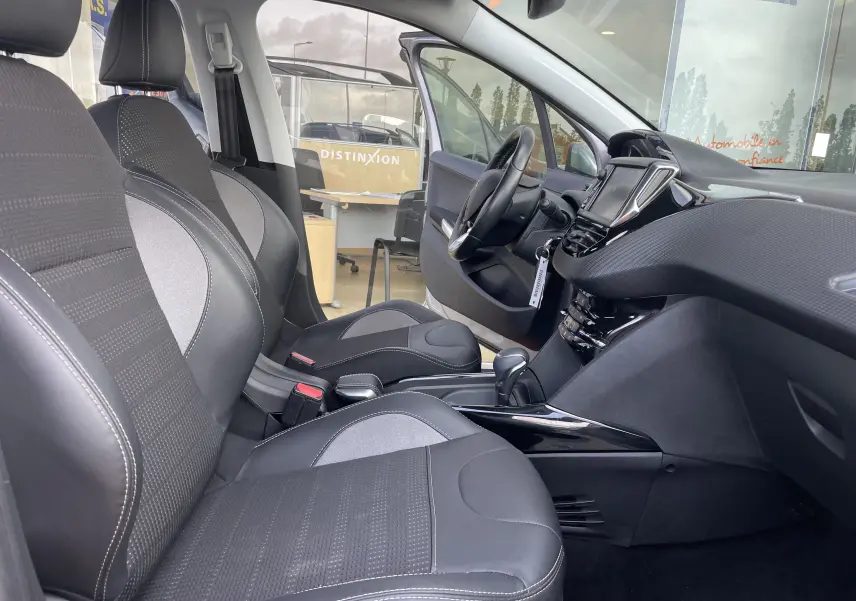 Intérieur avant droit du Peugeot 2008 gris 2019, sièges tissu et cuir gris-noir, tableau de bord moderne avec écran tactile.
