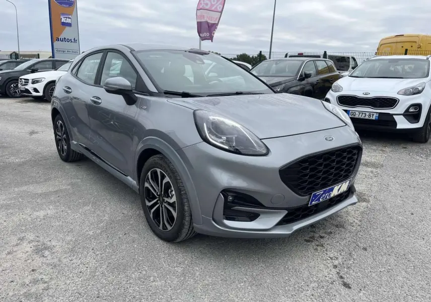 Ford Puma gris Solar vu en 3/4 avant droit sur un parking, avec calandre noire et jantes bicolores.