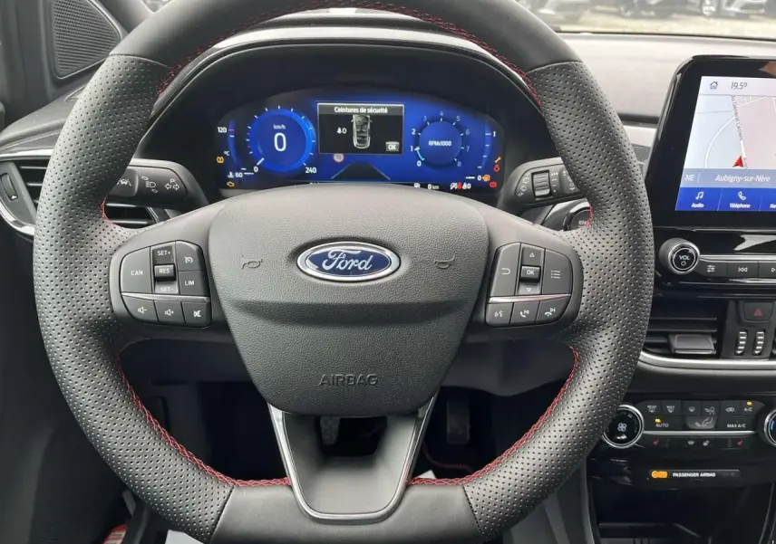 Vue rapprochée du volant perforé avec surpiqûres rouges et tableau de bord numérique du Ford Puma 2023.