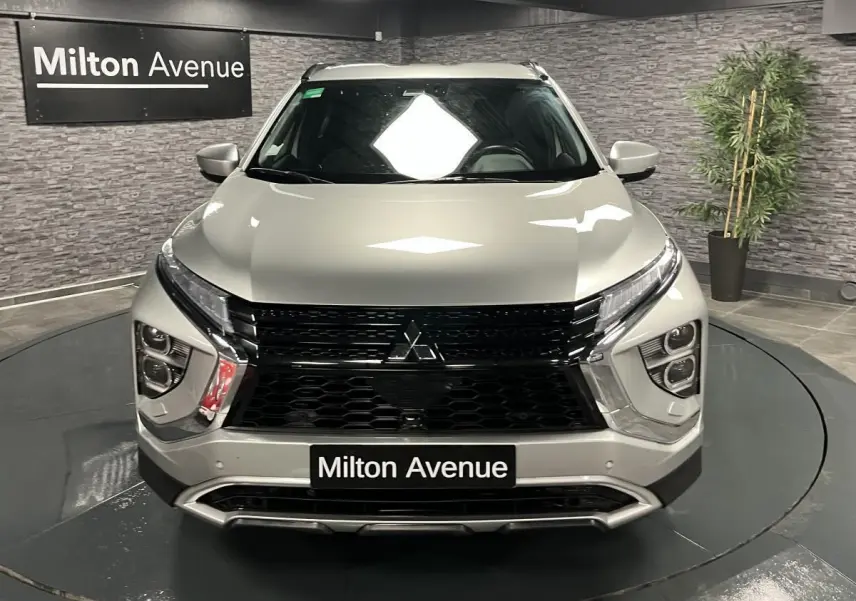 Vue frontale du Mitsubishi Eclipse Cross gris métallisé avec calandre noire et éclairage LED distinctif en intérieur showroom.