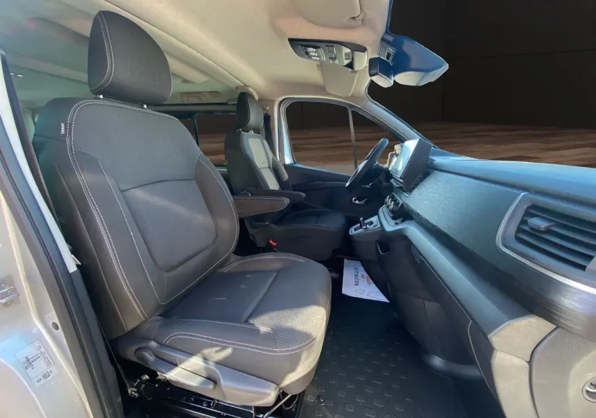Intérieur avant du Renault Trafic Combi gris Highland 2025, sièges tissu noir avec accoudoirs et tableau de bord moderne