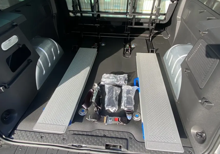 Vue intérieure arrière du coffre gris Highland du Renault Trafic Combi avec rampes et sangles de fixation au sol.