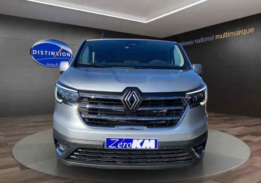 Vue de face d'un Renault Trafic Combi gris Highland avec calandre noire et feux LED allumés en showroom