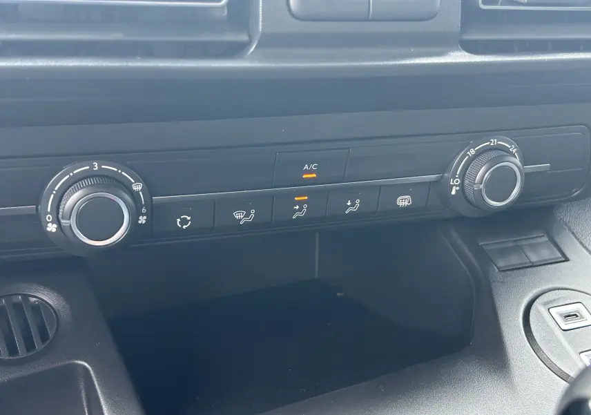 Gros plan sur la console centrale du Citroën Berlingo Fourgon 2025, avec commandes climatisation et ventilation noires.