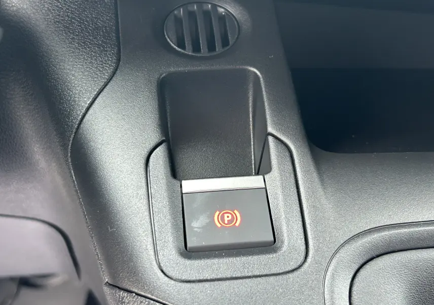Gros plan sur le bouton de frein à main électronique rouge dans l'habitacle noir du Citroën Berlingo Fourgon 2025.