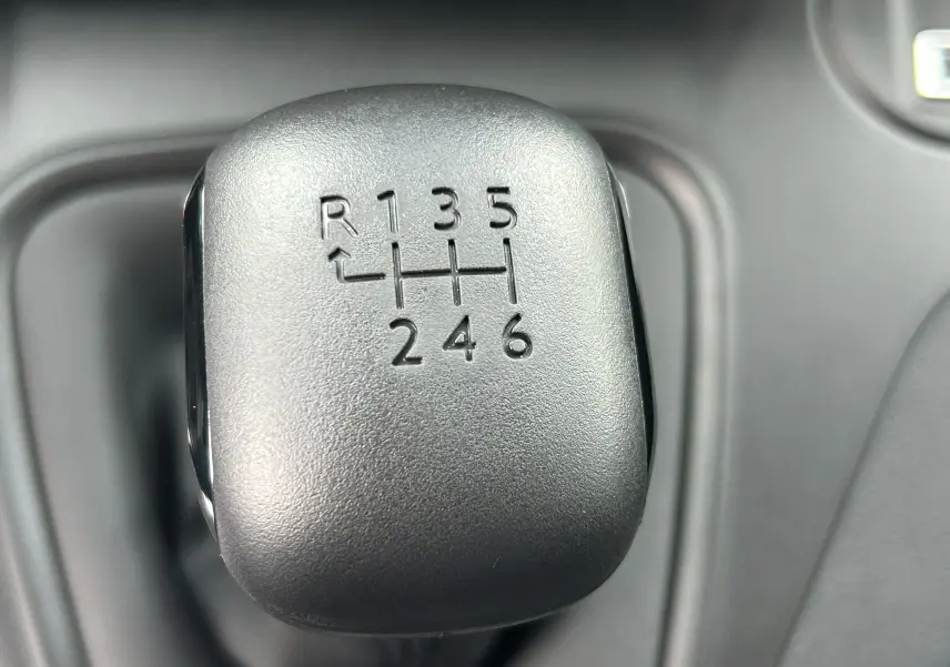 Gros plan sur le levier de vitesses manuel noir du Citroën Berlingo Fourgon blanc, montrant la grille à 6 rapports plus marche arrière.