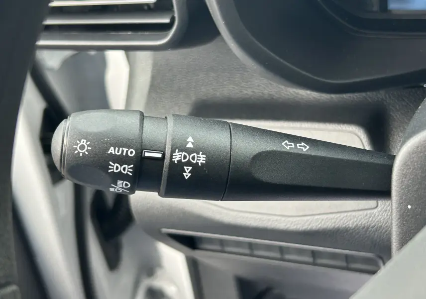 Gros plan sur la commande des feux et clignotants du Citroën Berlingo Fourgon blanc, côté gauche du volant.