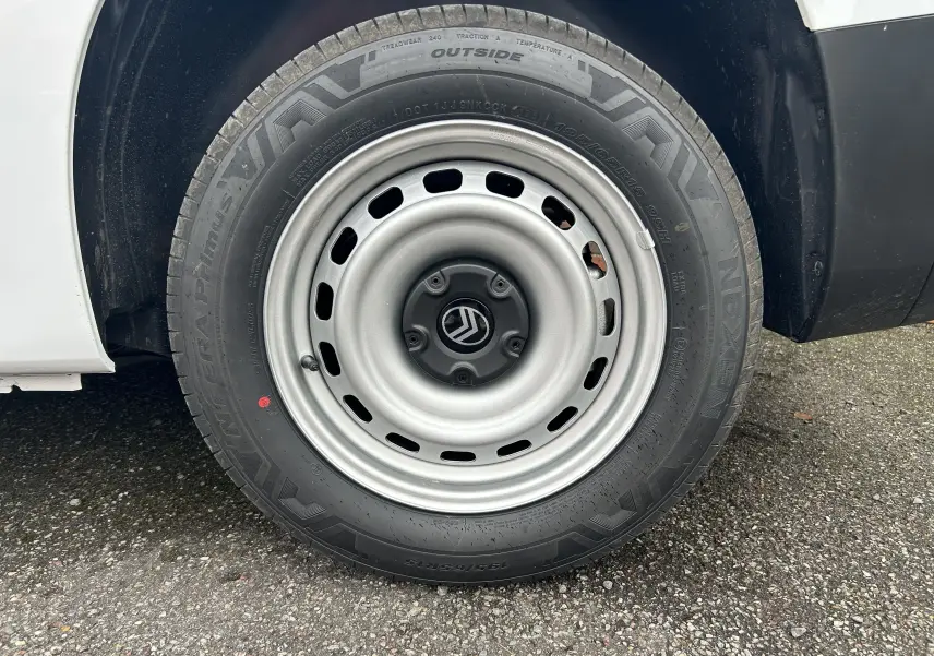 Gros plan sur la roue arrière droite d'un Citroën Berlingo Fourgon blanc avec jante acier et logo Citroën central.