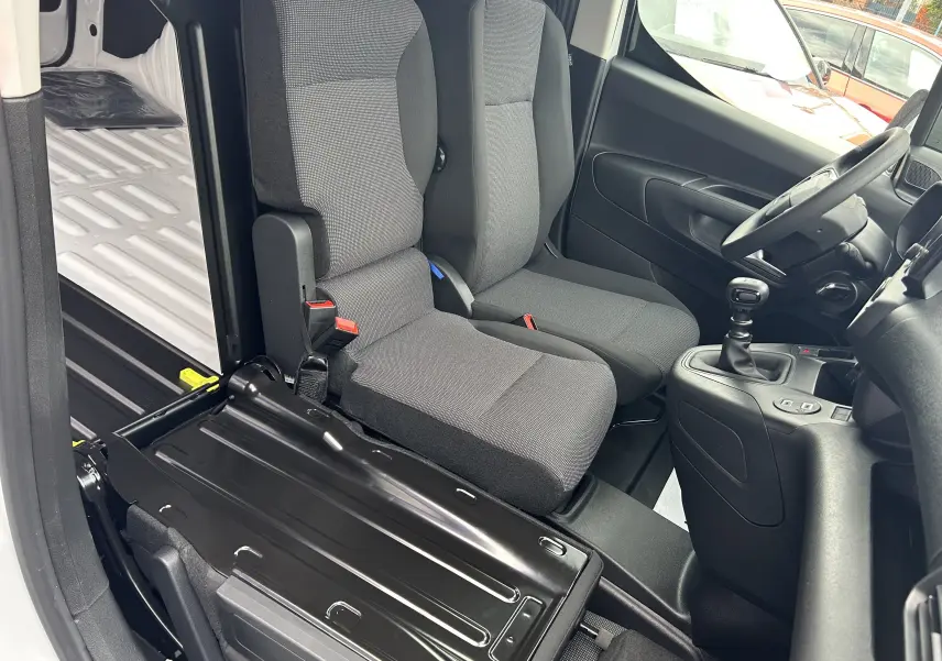 Vue intérieure côté droit du Citroën Berlingo Fourgon blanc 2025, montrant sièges avant en tissu et levier de vitesses manuel.
