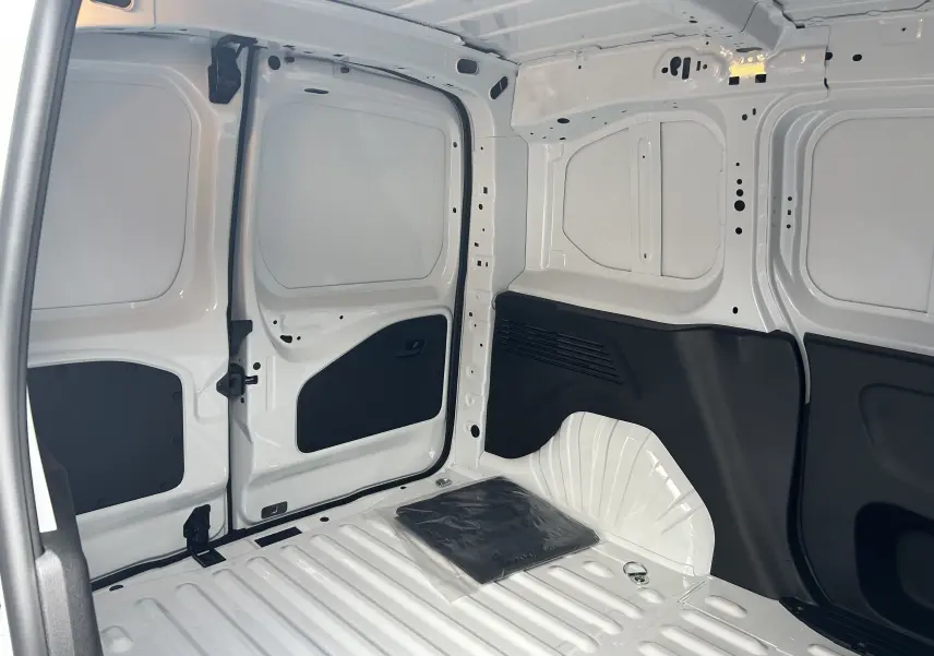 Intérieur du fourgon Citroën Berlingo BlueHDi 100 2025 en blanc, vue de la zone de chargement avec parois métalliques et protections noires.