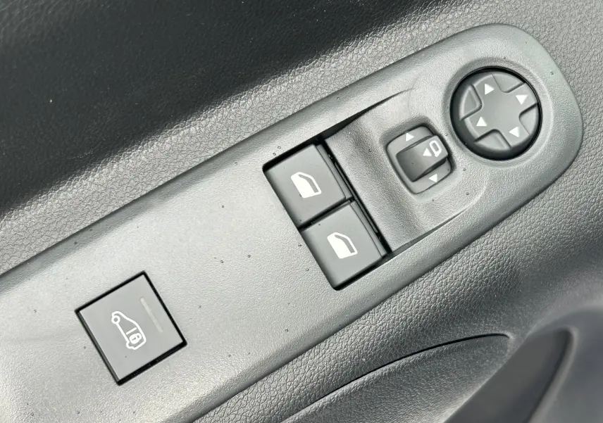Gros plan sur les commandes de lève-vitres et réglage des rétroviseurs côté conducteur du Citroën Berlingo Fourgon blanc 2025.