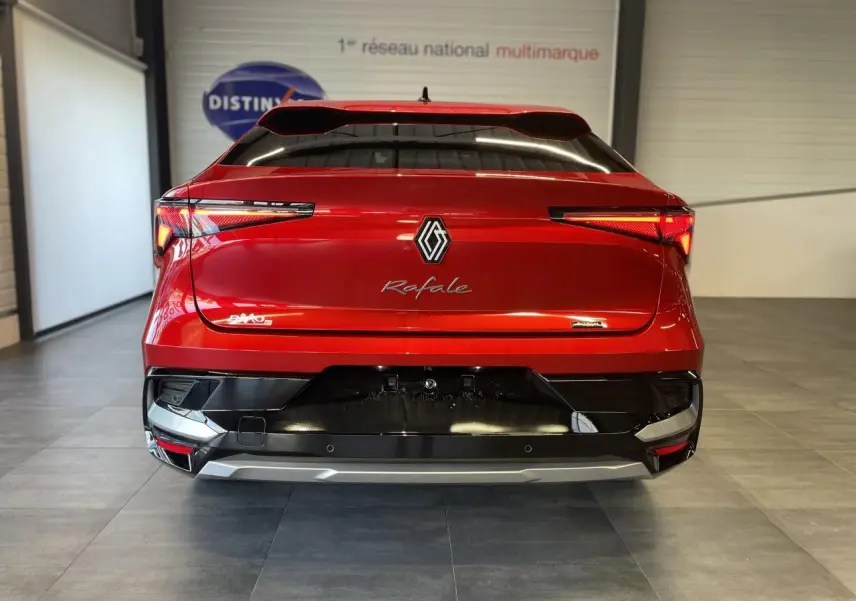 Vue arrière d'une Renault Rafale rouge à toit noir avec feux LED et logo central dans un showroom.