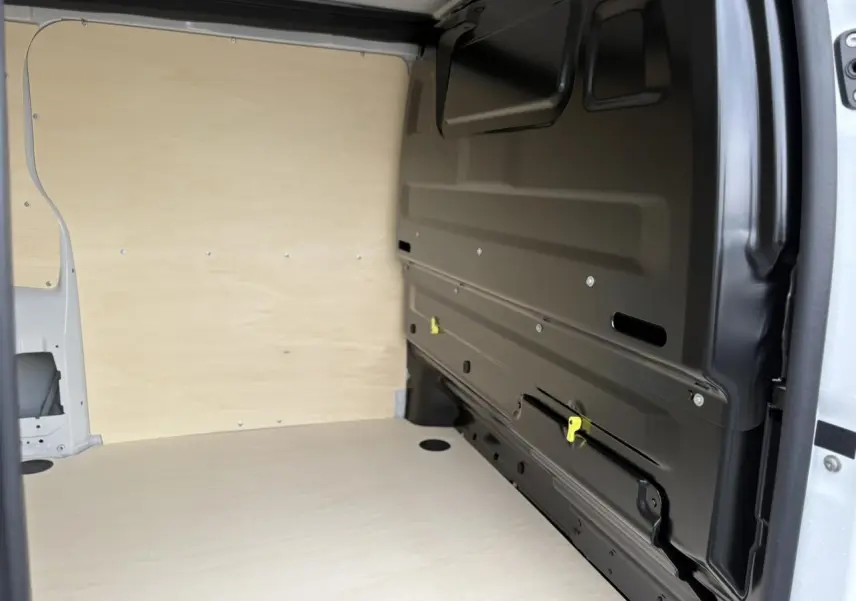 Vue intérieure de la zone de chargement du Peugeot Expert Fourgon blanc Icy, avec cloison bois et paroi latérale noire.