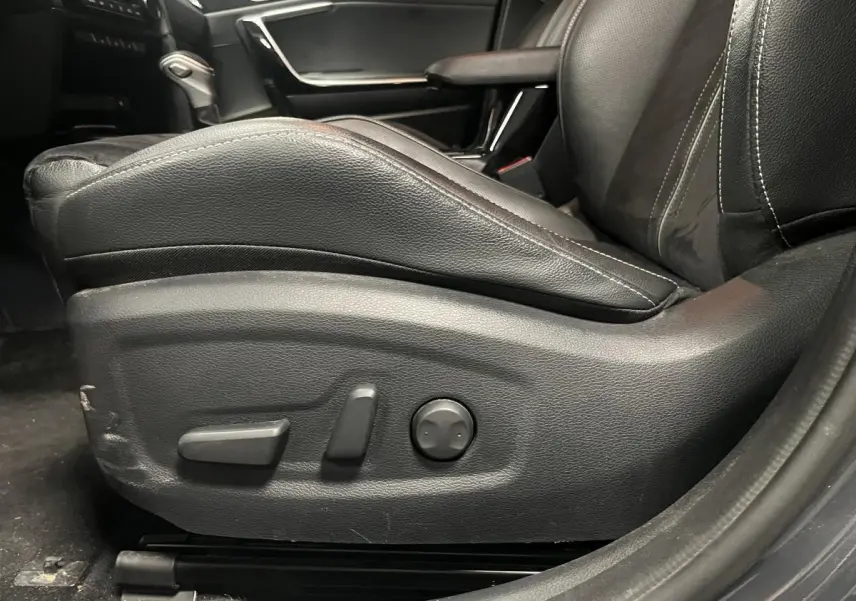 Gros plan sur le siège conducteur en cuir noir avec commandes électriques dans l'habitacle d'une Kia Ceed 2023.