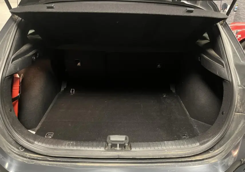 Coffre ouvert vu de l'arrière d'une Kia Ceed gris, montrant l'espace de chargement vide et les finitions intérieures.