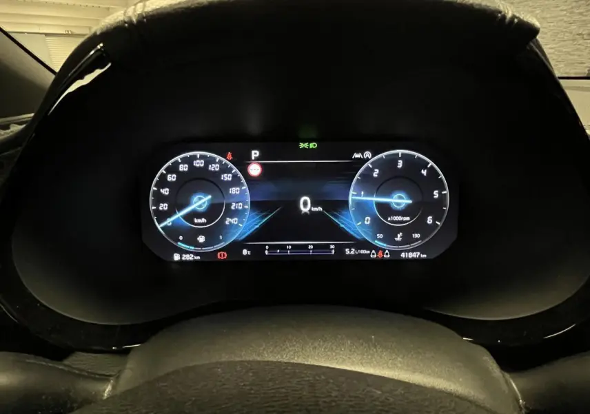 Combiné d'instrumentation digital bleu affichant la vitesse et le régime dans une Kia Ceed 2023 gris, vue depuis le volant.