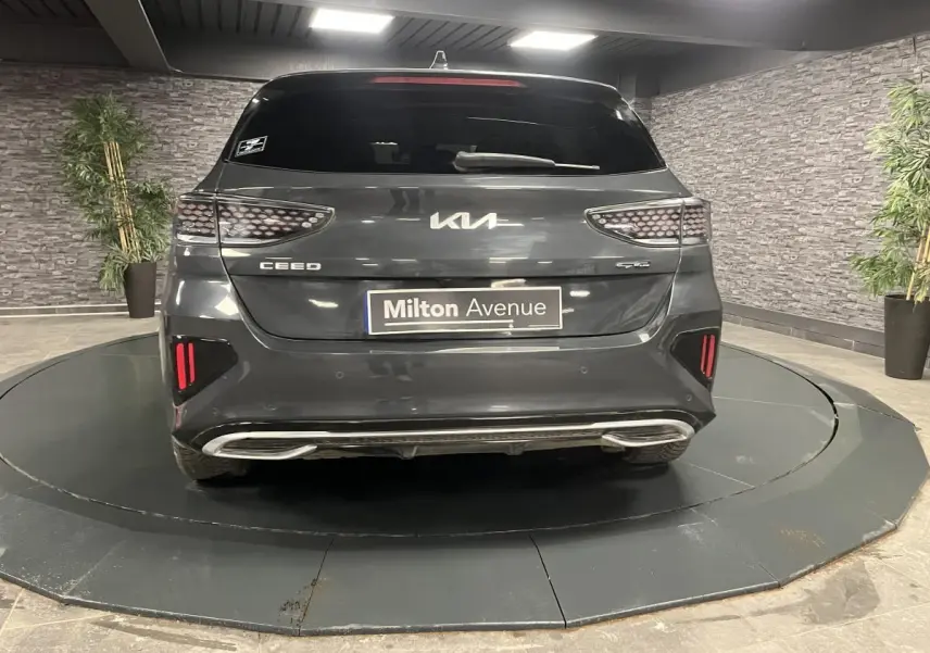 Vue arrière d'une Kia Ceed gris métallisé GT Line avec feux arrière en nid d'abeille et double sortie d'échappement intégrée.