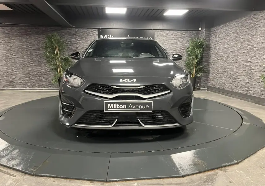 Vue frontale d'une KIA Ceed 2023 gris métallisé avec calandre noire et détails chromés en showroom.